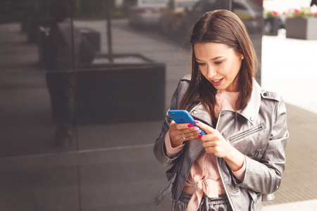 Young woman using her phone at the office buildingの写真素材