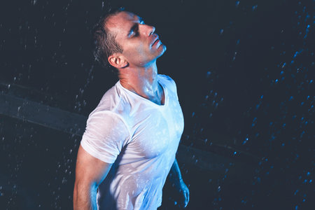 Fresh portrait of muscular man with water splashes on dark background.の写真素材