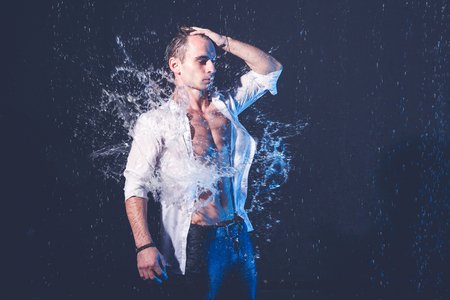 Fresh portrait of muscular man with water splashes on dark background.の写真素材
