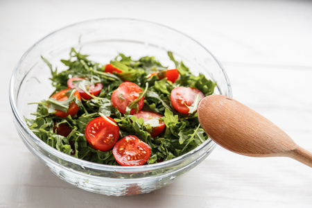 salad with arugula and tomatoes in the glass plateの写真素材