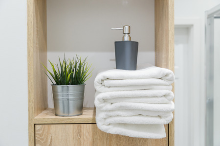 Shelf in bathroom with white towels, greens and bottleの写真素材