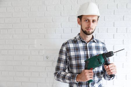 Man repairer in protective hard hat with hsmmer drillの写真素材