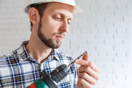 Repairman working with power drill. Looking at broken bitの写真素材