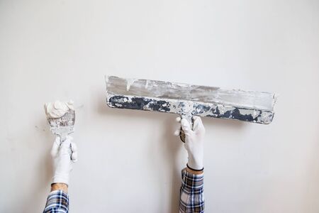Worker in white gloves performs plastering of the walls of the roomの写真素材