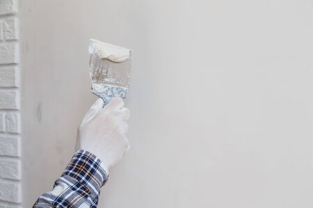 Worker in white gloves performs plastering of the walls of the roomの写真素材