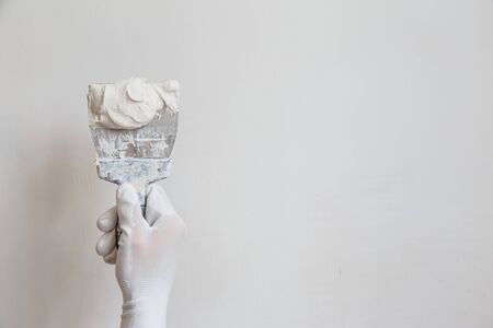 Worker in white gloves performs plastering of the walls of the roomの写真素材