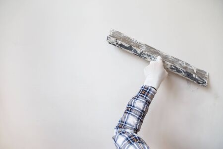 Worker in white gloves performs plastering of the walls of the roomの写真素材