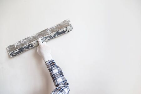Worker in white gloves performs plastering of the walls of the roomの写真素材