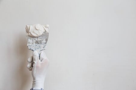 Worker in white gloves performs plastering of the walls of the roomの写真素材
