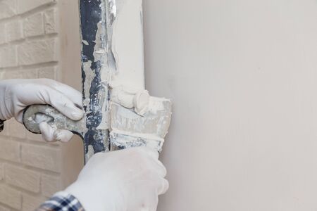 Worker in white gloves performs plastering of the walls of the roomの写真素材