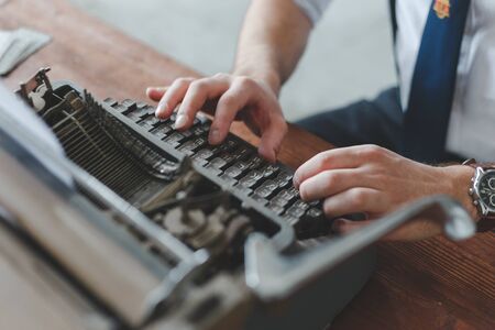 Man working on retro typewriter at desk in parlor room.の写真素材