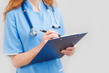 Female doctor writes notes on the clipboardの写真素材