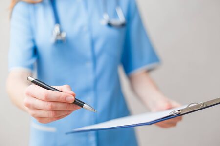 Doctor giving blank clipboard and pen to signingの写真素材