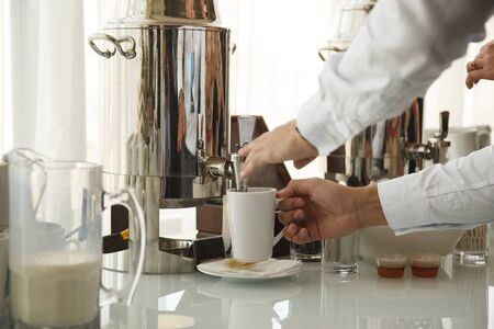 Pouring coffee from metal pot at cateringの写真素材