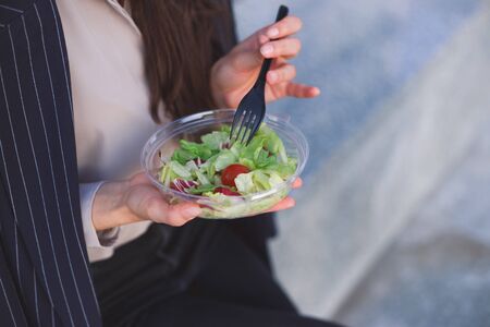 Office worker eats salad sitting outdoorの写真素材