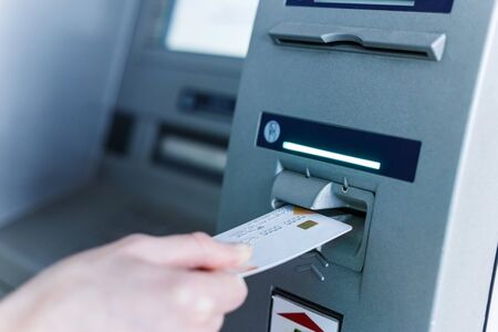 Person insert card to automated teller machine. Cashing non-cash money by individualの写真素材