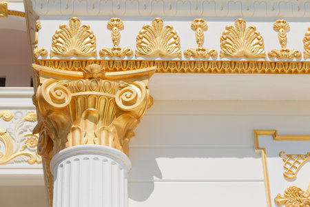 Top part of pillar, white column with golden top, exnterior detail.