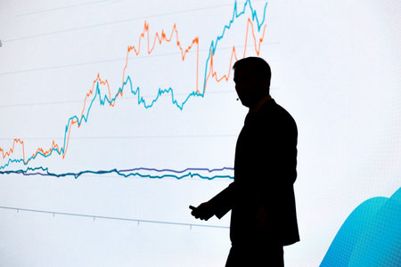Silhouette of speaker at public business conference with graph in background