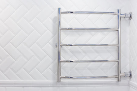 Heated towel rail with side connection in a white brick tiled bathroom.