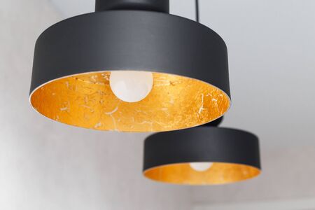 Two black metal pendant lights decorated inside by golden foil.の写真素材