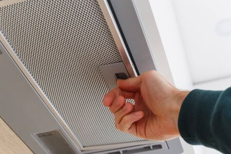 Man removing a filter from cooker hood for cleaning or service.. Close upの写真素材
