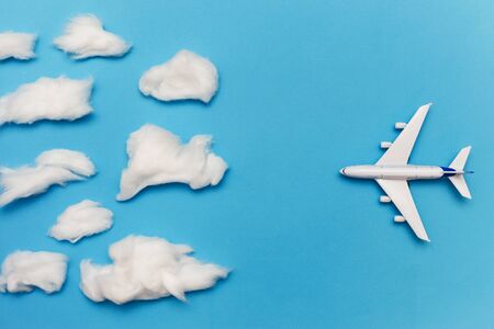 Toy plane on blue background flies to overcast. Flat lay of bad weather and transportation and travel conceptの写真素材