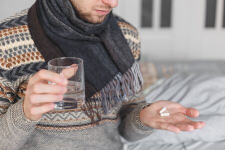 Man holding a glass of water and pills, detail.の写真素材