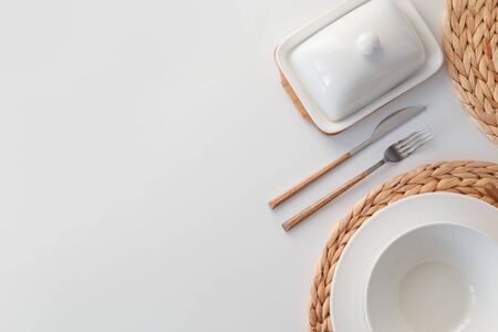 White ceramic tableware, fibre braided round placemat and cutlery set on white background. Scandinavian styleの写真素材