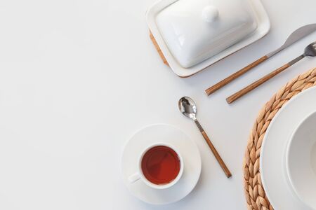 White ceramic tableware, fibre braided round placemat and cutlery set on white background. Scandinavian style.の写真素材