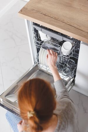 Housework: young woman putting dishes in the dishwasherの写真素材