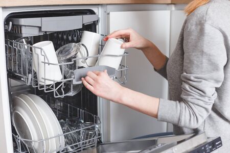 Housework: young woman putting dishes in the dishwasher.の写真素材