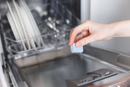 Woman putting tablet in dishwasher detergent boxの写真素材
