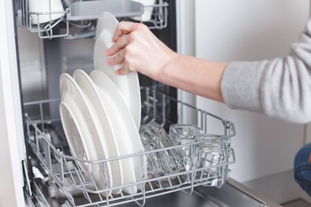 Housework: young woman putting dishes in the dishwasherの写真素材