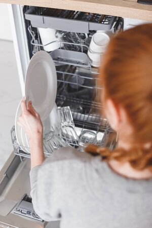 Housework: young woman putting dishes in the dishwasherの写真素材