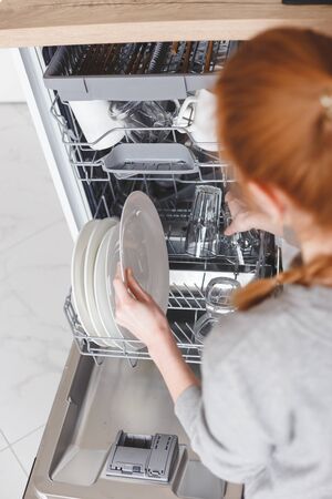 Housework: young woman putting dishes in the dishwasherの写真素材