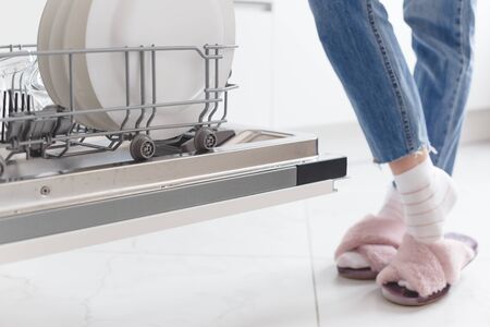 Contemporary housewife: woman standing near dishwasher in the kitchen.の写真素材