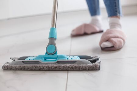 Housewife mopping floor made of porcelain tiles in the kitchen. Close-up viewの写真素材