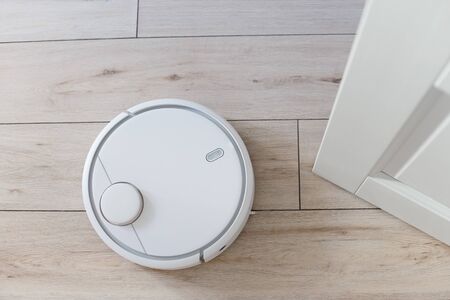Home vacuum cleaning robot in action near by door living roomの写真素材