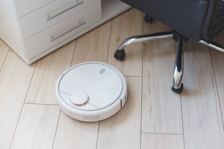 Robot vacuum cleaner vacuuming floor in office.の写真素材