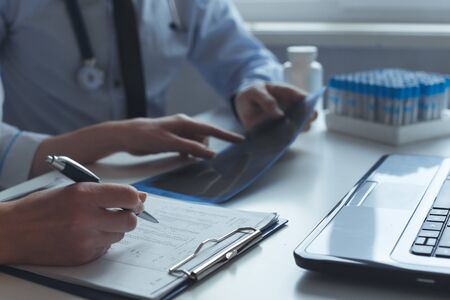 Close up of hands of patient and doctor consultation prescribing treatment. Works with x-ray and medical tests.の写真素材