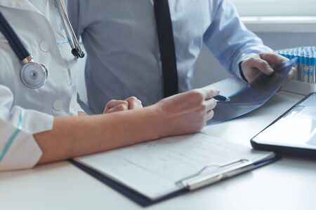 Close up of hands of patient and doctor consultation prescribing treatment. Works with x-ray and medical testsの写真素材