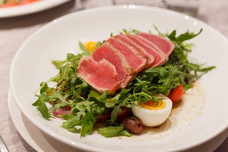 Meat carpaccio with arugula olives and soft-boiled egg. Serving in a restaurant.の写真素材