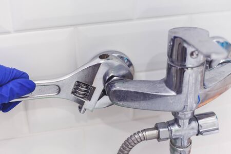 Plumber uses pipe wrench for service shower mixer tap.の写真素材
