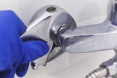 Plumber uses pipe wrench for service shower mixer tap.の写真素材