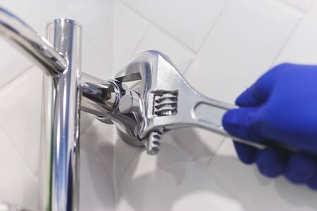 Amateur novice plumber uses the wrong pipe wrench for a heated towel rail in a bathroom home.の写真素材