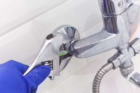 Plumber uses pipe wrench for service shower mixer tap.の写真素材