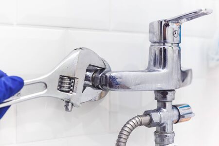 Plumber uses pipe wrench for service shower mixer tap.の写真素材