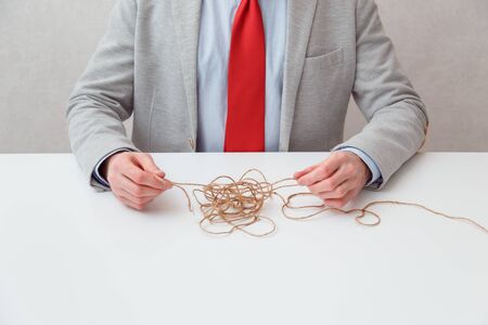 Alone businessman try to unwinds tangled thread ball like puzzle out situation. Conceptual photo.の写真素材