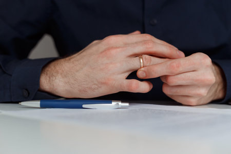 Young man is taking off the wedding ring. Close up view. Divorce concept