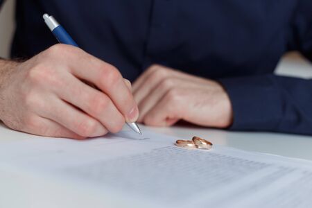 husband signing divorce agreement and woman push away weeding ringの写真素材